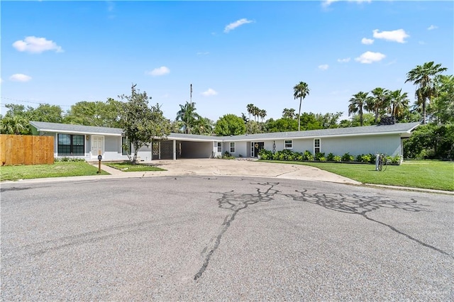 single story home with an attached carport, a front yard, fence, and driveway