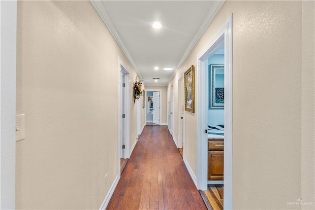 hall with a textured wall, dark wood-style flooring, baseboards, and ornamental molding