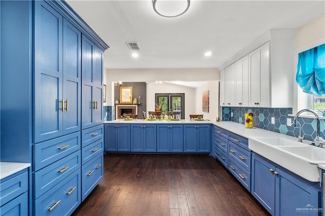 kitchen featuring visible vents, a sink, dark wood-style floors, light countertops, and decorative backsplash