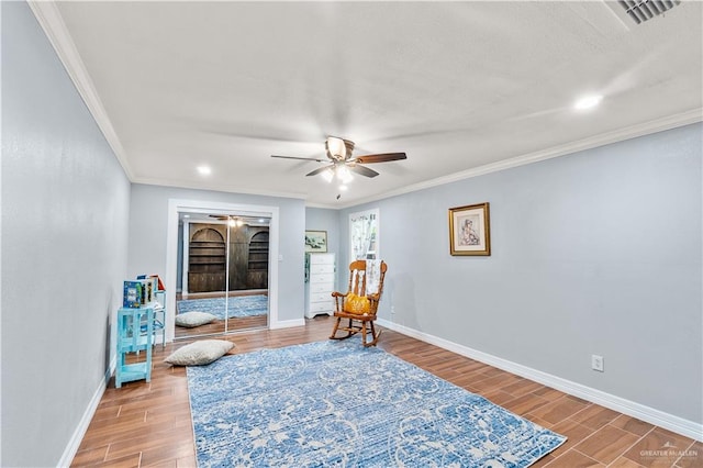 living area featuring ceiling fan, baseboards, wood finished floors, and crown molding