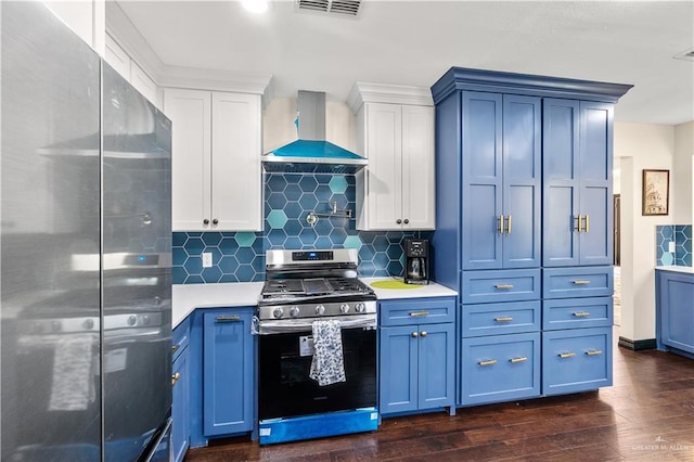 kitchen featuring dark wood-style flooring, light countertops, appliances with stainless steel finishes, wall chimney exhaust hood, and blue cabinets