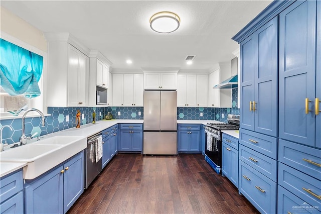 kitchen featuring visible vents, a sink, blue cabinetry, stainless steel appliances, and wall chimney exhaust hood