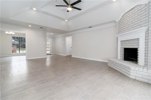 unfurnished living room with a tray ceiling, a fireplace, ceiling fan with notable chandelier, and ornamental molding