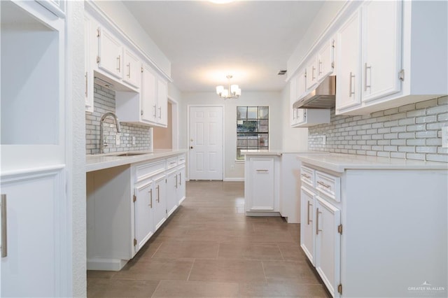 kitchen featuring backsplash, white cabinetry, hanging light fixtures, and sink