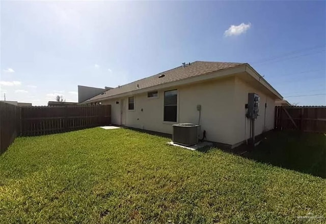 back of property with a yard and central AC