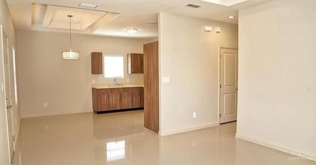 spare room with a tray ceiling and light tile patterned flooring