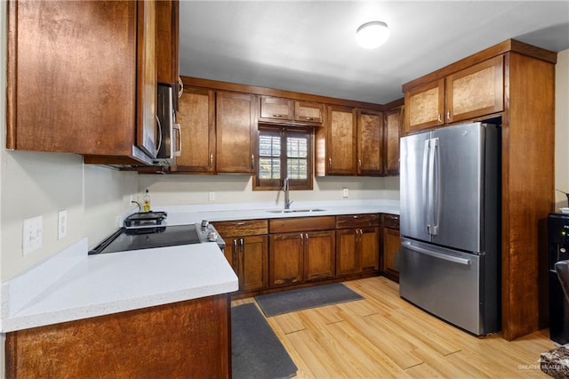 kitchen with sink, appliances with stainless steel finishes, and light wood-type flooring