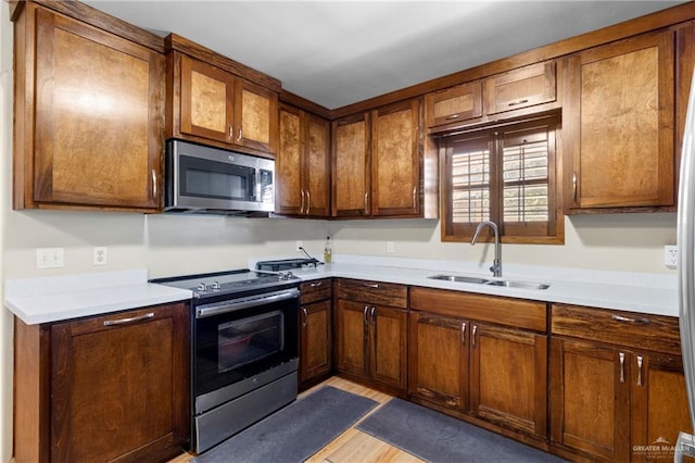 kitchen featuring stainless steel appliances, light hardwood / wood-style flooring, and sink