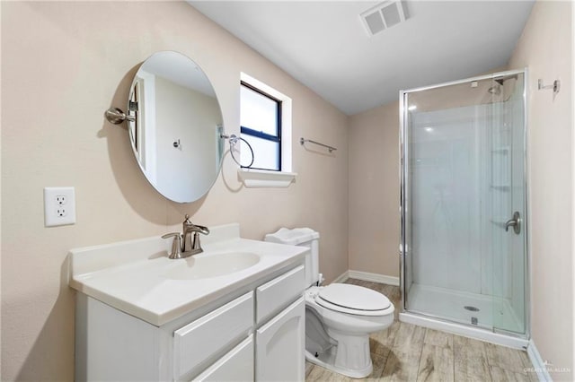 bathroom featuring toilet, vanity, a shower with door, and hardwood / wood-style flooring