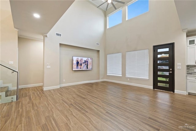 1518 Tierra Bella, Weslaco, TX 78596 - unfurnished living room featuring stairs, a ceiling fan, light wood-style flooring, baseboards, and a high ceiling