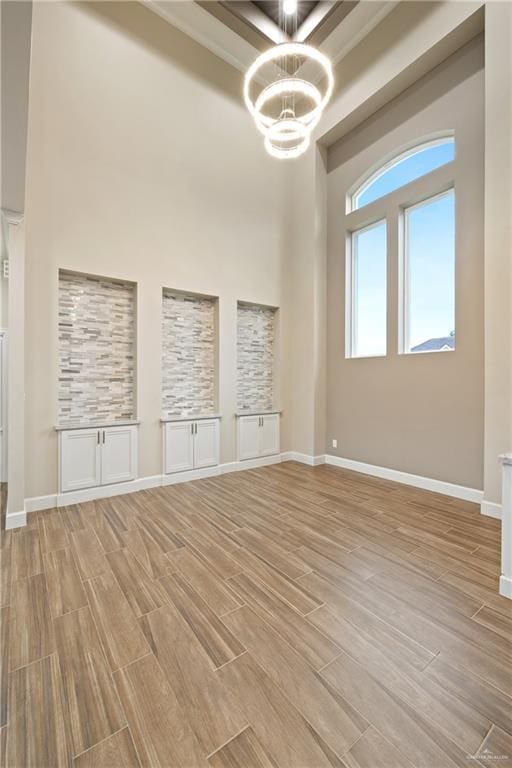 1518 Tierra Bella, Weslaco, TX 78596 - unfurnished room featuring light wood-type flooring, a chandelier, a high ceiling, and baseboards