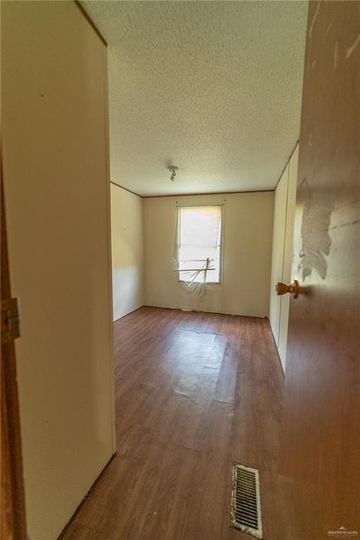 empty room with wood-type flooring and a textured ceiling