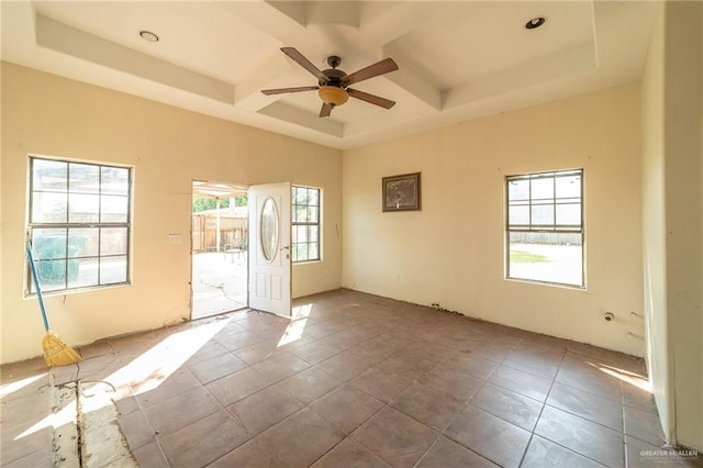 empty room featuring tile patterned flooring, plenty of natural light, ceiling fan, and a tray ceiling