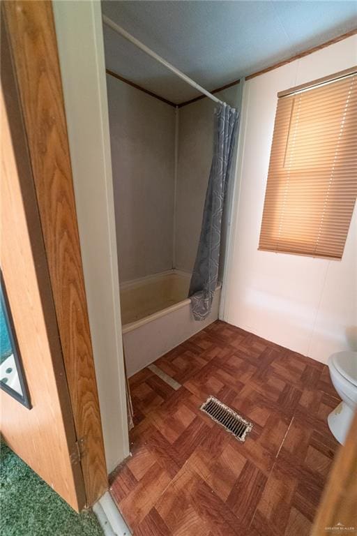 bathroom featuring shower / bath combo, toilet, and parquet floors