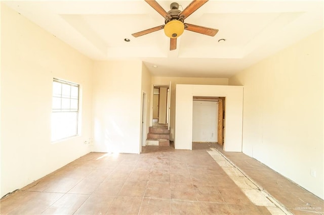 spare room featuring ceiling fan and a raised ceiling