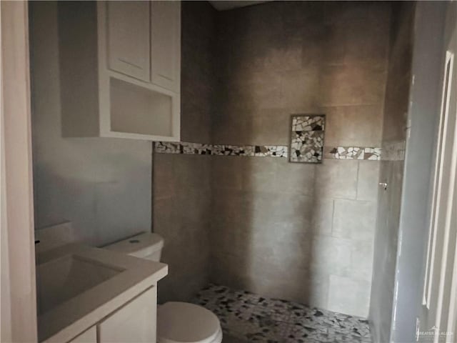 bathroom with vanity, toilet, and a tile shower