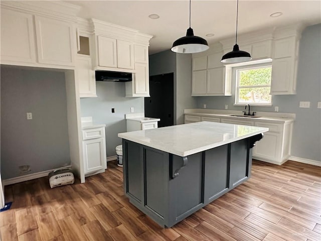 kitchen featuring sink, a center island, hanging light fixtures, white cabinets, and light wood-type flooring