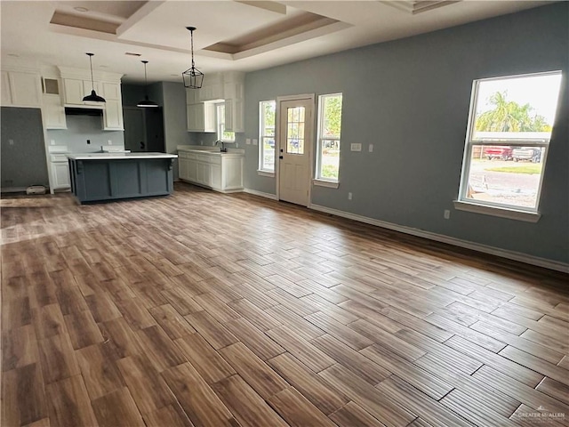 kitchen featuring white cabinets, pendant lighting, light wood-type flooring, and a center island