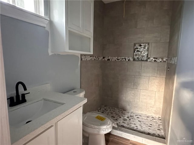 bathroom featuring tiled shower, vanity, and toilet