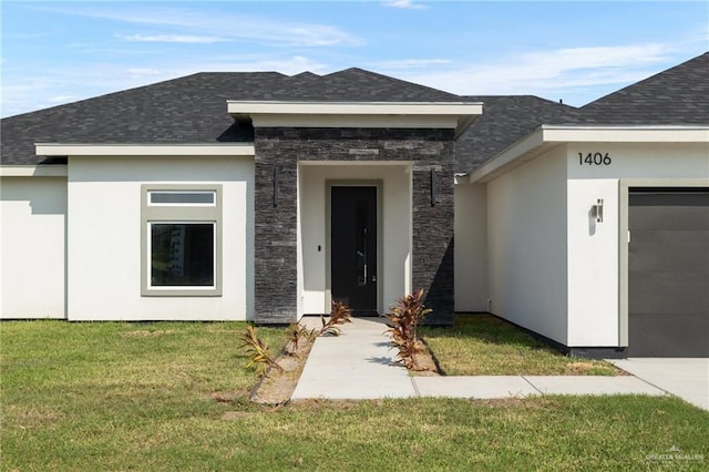 view of exterior entry with a shingled roof, stucco siding, a garage, a yard, and stone siding