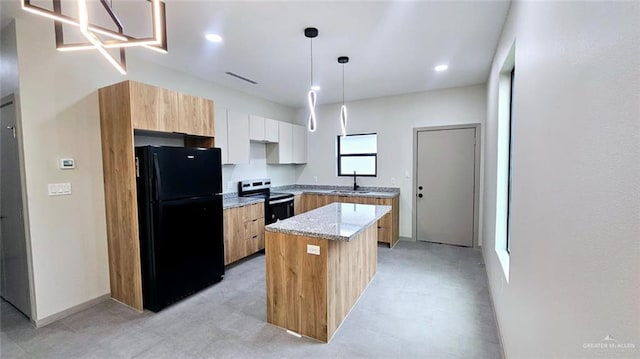 kitchen with a center island, decorative light fixtures, range with electric cooktop, white cabinets, and black fridge