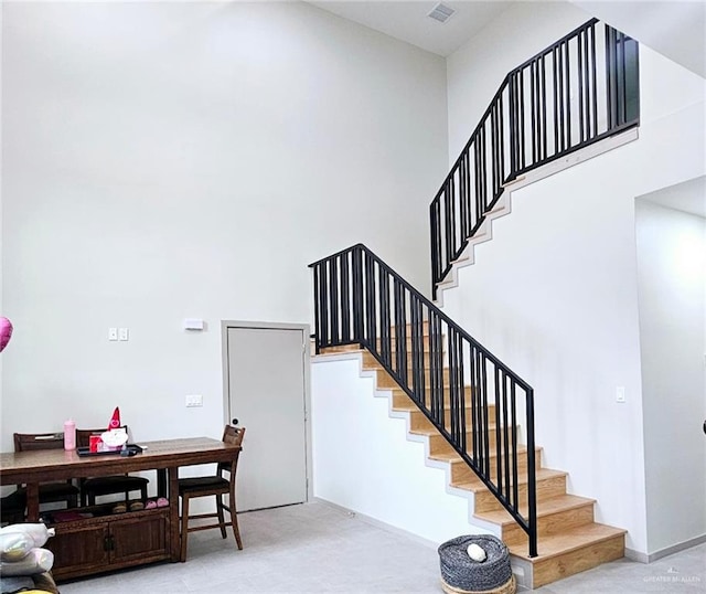 staircase featuring carpet floors and a high ceiling