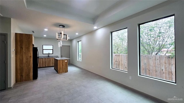 kitchen with a kitchen island, hanging light fixtures, and black fridge