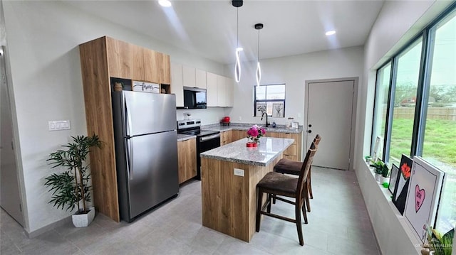 kitchen with appliances with stainless steel finishes, pendant lighting, a breakfast bar, a center island, and white cabinetry