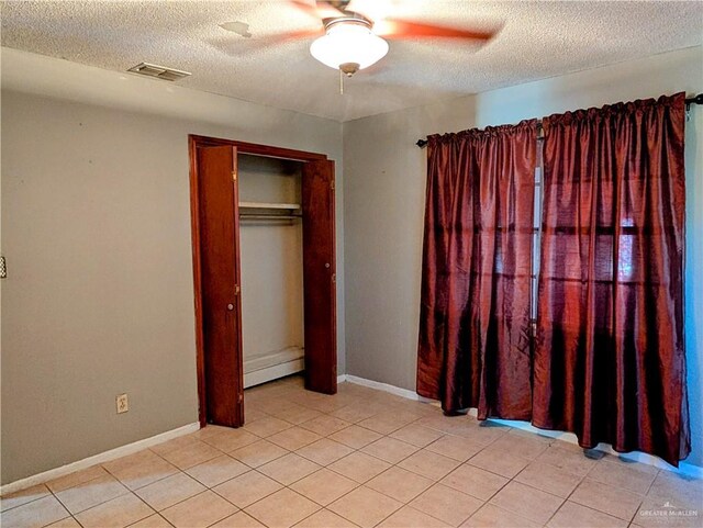 605 8th St, Hidalgo, TX 78557 - unfurnished bedroom featuring a textured ceiling, light tile patterned floors, ceiling fan, baseboards, and a closet