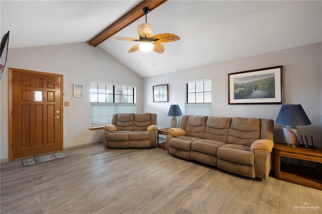 living room featuring ceiling fan, lofted ceiling with beams, a textured ceiling, and light wood-type flooring