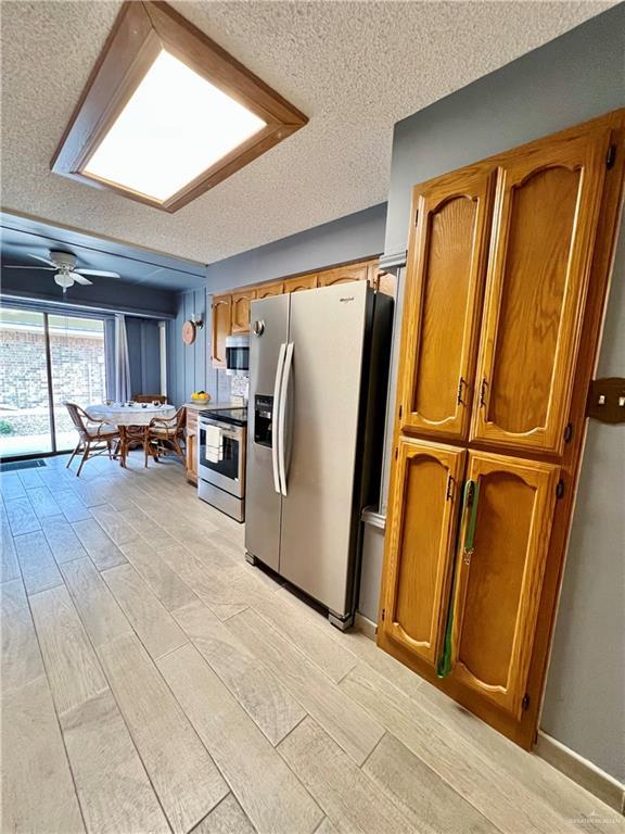 kitchen featuring stainless steel appliances, a textured ceiling, and ceiling fan