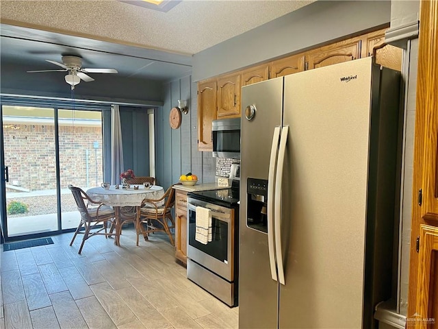 kitchen featuring ceiling fan, appliances with stainless steel finishes, light brown cabinetry, and a textured ceiling