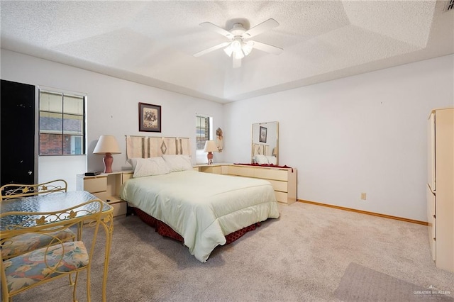 carpeted bedroom featuring multiple windows, ceiling fan, a tray ceiling, and a textured ceiling