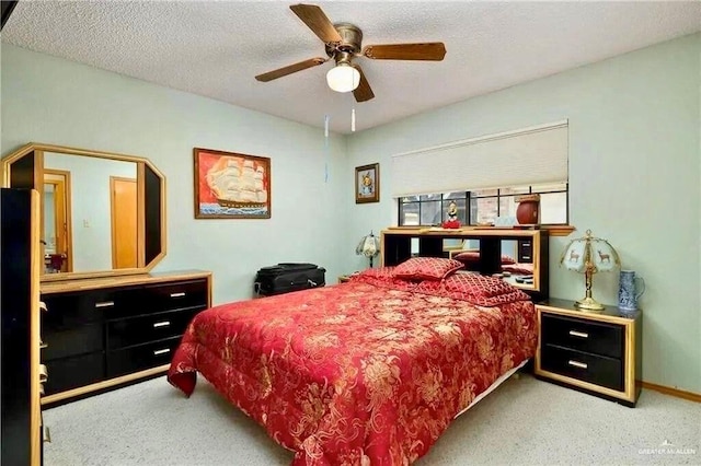 bedroom with ceiling fan, light colored carpet, and a textured ceiling