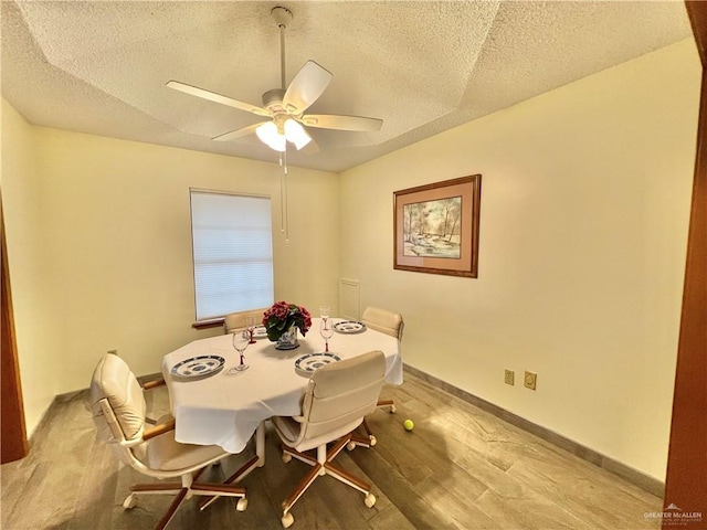 dining space featuring ceiling fan, wood-type flooring, and a textured ceiling