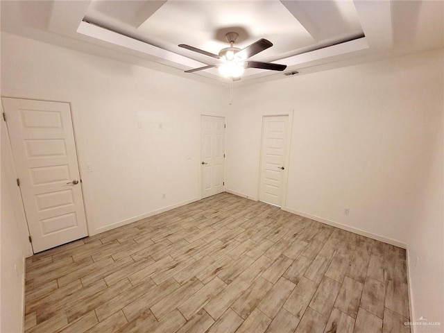 spare room featuring ceiling fan, a raised ceiling, and light wood-type flooring