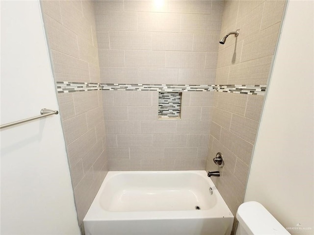 bathroom with tiled shower / bath combo and toilet