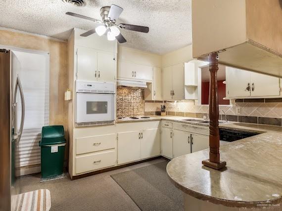 131 N Missouri Ave, Mercedes, TX 78570 - kitchen with oven, a textured ceiling, freestanding refrigerator, a ceiling fan, and decorative backsplash