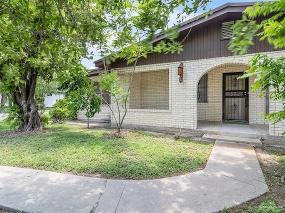 131 N Missouri Ave, Mercedes, TX 78570 - exterior space with a porch, brick siding, and a yard