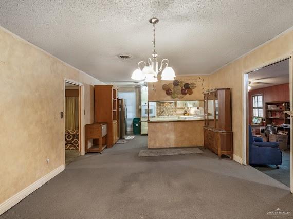 131 N Missouri Ave, Mercedes, TX 78570 - kitchen featuring an inviting chandelier, light carpet, freestanding refrigerator, a peninsula, and baseboards