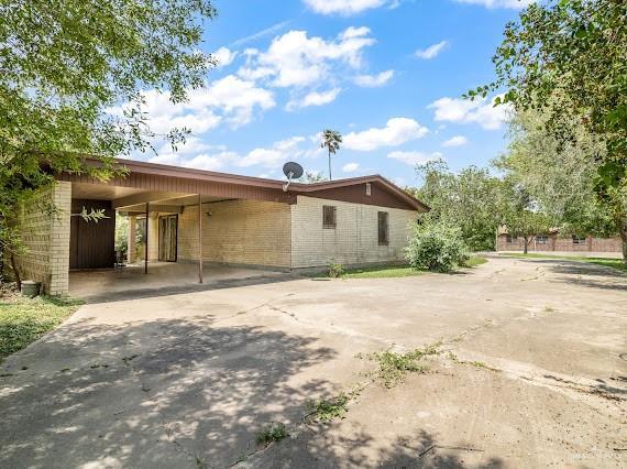 131 N Missouri Ave, Mercedes, TX 78570 - rear view of property with brick siding, a carport, and concrete driveway