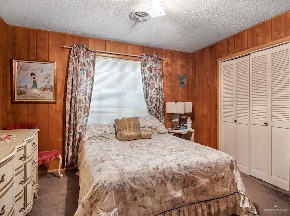 131 N Missouri Ave, Mercedes, TX 78570 - bedroom with a closet, a textured ceiling, carpet, and wooden walls