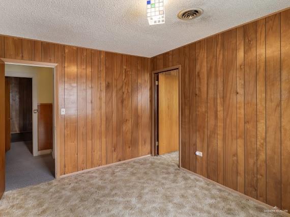 131 N Missouri Ave, Mercedes, TX 78570 - carpeted spare room featuring visible vents, a textured ceiling, and wooden walls