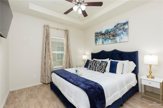 bedroom featuring wood-type flooring, a raised ceiling, and ceiling fan