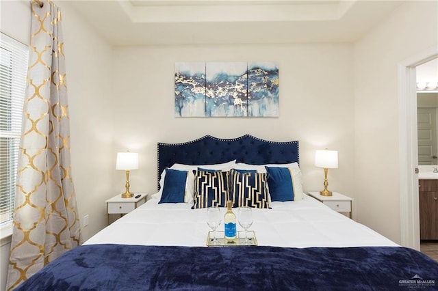 bedroom featuring connected bathroom and a tray ceiling