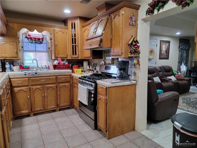 3300 Pradera St, Mission, TX 78574 - kitchen featuring gas range, tile counters, a sink, light tile patterned floors, and brown cabinetry