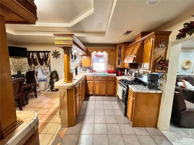 3300 Pradera St, Mission, TX 78574 - kitchen featuring gas stove, decorative columns, tile counters, brown cabinets, and a sink