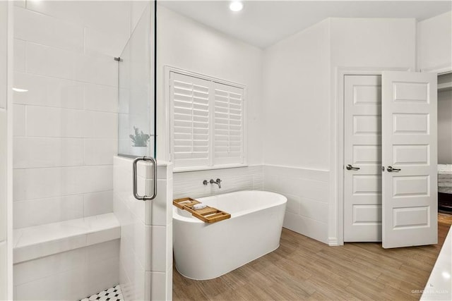 16593 W Mccullar Ct, Harlingen, TX 78552 - bathroom with a stall shower, a freestanding bath, wood finished floors, tile walls, and recessed lighting