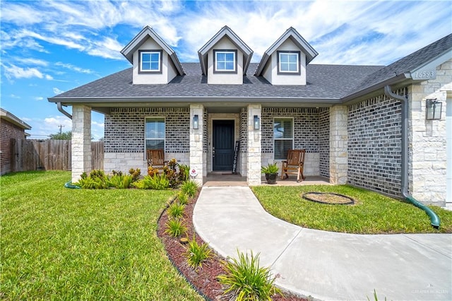 16593 W Mccullar Ct, Harlingen, TX 78552 - view of front of house featuring a shingled roof, stone siding, brick siding, and a porch