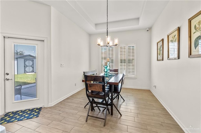 16593 W Mccullar Ct, Harlingen, TX 78552 - dining area featuring a chandelier, a raised ceiling, light wood finished floors, and baseboards